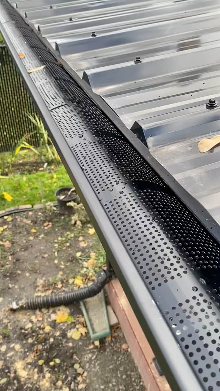 Protège-gouttières perforé en aluminium noir installé sur une gouttière de maison dans l'Ouest-de-l'Île