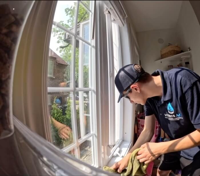 Technicien VitresMV qui lave une fenêtre à carreaux de l'intérieur d'une maison dans l'Ouest-de-l'Île